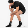 Man wearing black socks with text sitting on a white surface