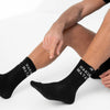 Person wearing black socks with visible branding on a white background