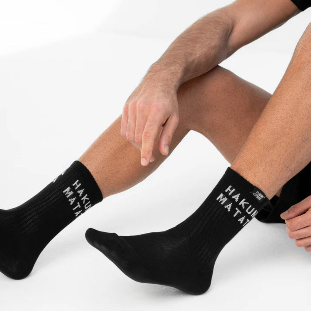 Person wearing black socks with visible branding on a white background