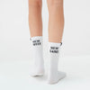 White socks with 'New Week' and 'New Gains' text worn by a person on a light gray background