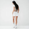 Woman wearing a white t-shirt and shorts on a plain background