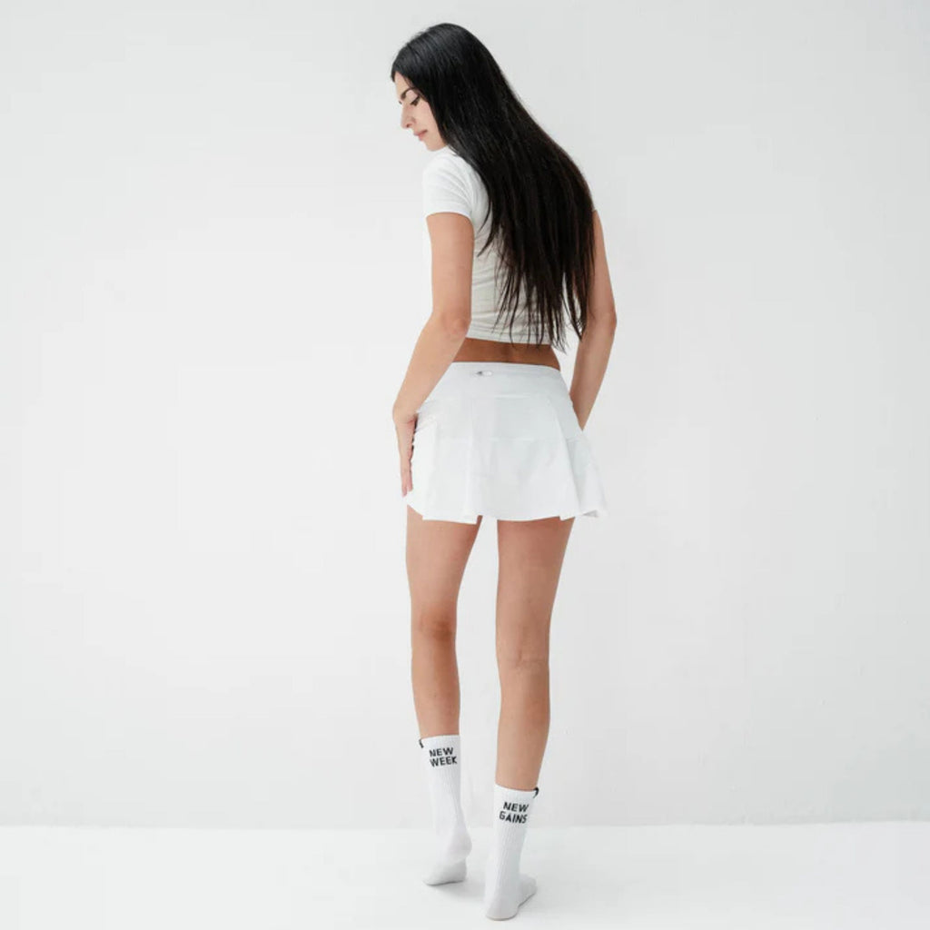 Woman wearing a white t-shirt and shorts on a plain background
