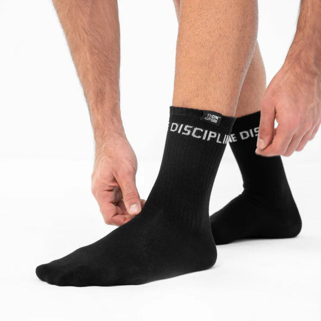 Black socks with 'Discipline' branding worn by a person on a white background