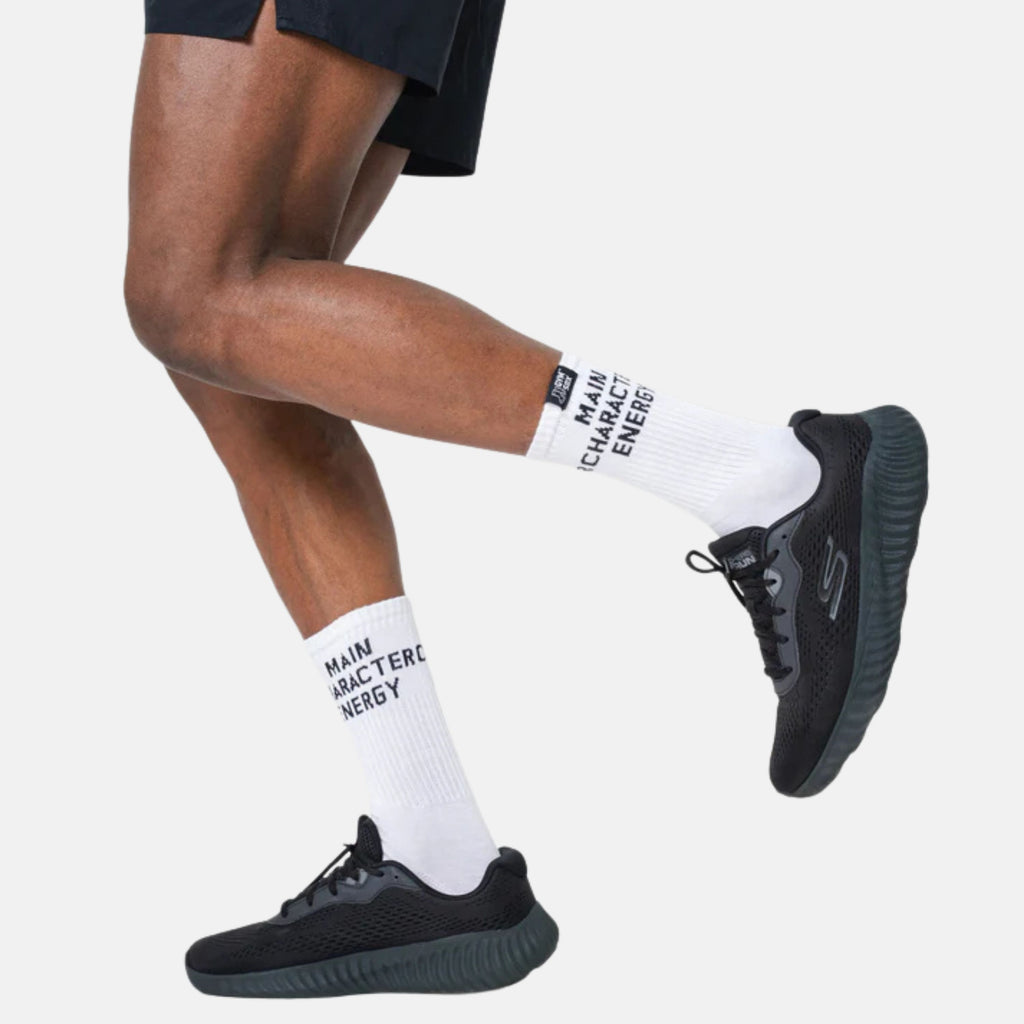 Person wearing black sneakers and white socks with text on a light gray background