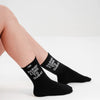 Black socks with 'Habibi Come To Dubai' text worn by a person on a white background