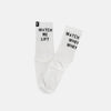 A pair of white crew socks with black text printed on the sides. One sock reads 'WATCH ME LIFT' and the other reads 'WATCH WHEY WHEY'.
