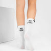 White crew socks worn on a person's feet, featuring black text that reads 'NO RISK' on one sock and 'NO STORY' on the other, photographed against a clean white studio background.