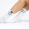 White crew socks worn on a person's feet, featuring the text 'CHEAT DAY' printed in black on the sides and a small black brand tag near the cuff.