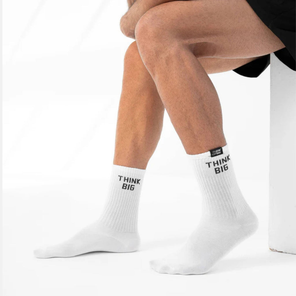 White socks with 'Think Big' text worn by a person on a white background