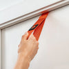 Hand using an orange door anchor strap on a white door.