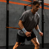 A man training in a gym with a resistance band attached to a belt.