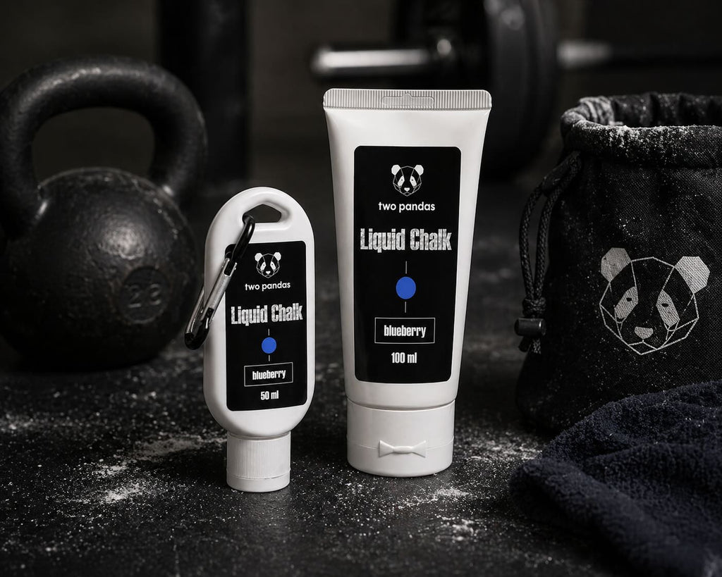 Two bottles of two pandas Liquid Blueberry Scented Chalk on a black surface with a kettlebell in the background.