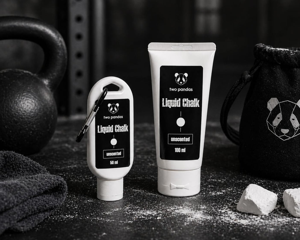 Two bottles of two pandas Liquid Unscented Chalk on a dark surface with gym equipment in the background.