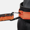 Close-up of an orange and black resistance band attached to a black belt on a light gray background