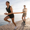 Two people exercising outdoors by a body of water.