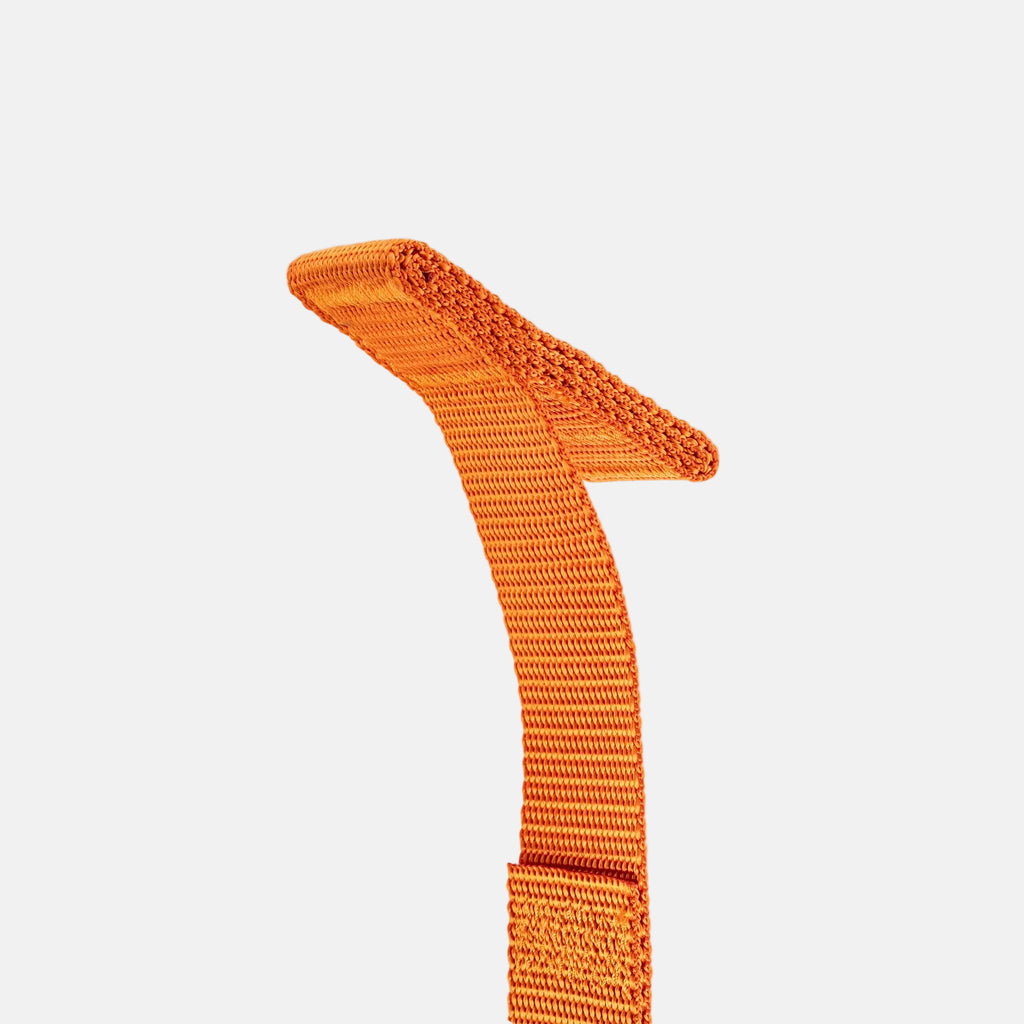 Detail of an orange webbing band on a light gray background