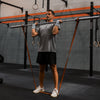 Man lifting a barbell in a gym setting with various equipment in the background.