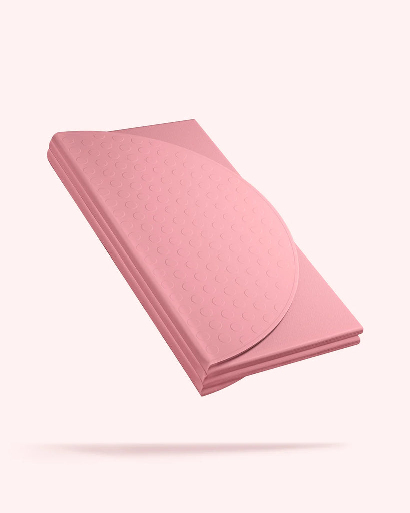 Folded pink Bala Compact yoga mat on a white background