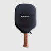 Black pickleball paddle with wooden handle on a light gray background