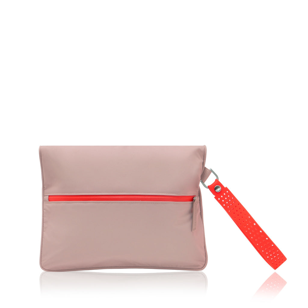 A blush pink nylon clutch bag with a bright red horizontal zipper and a matching red perforated wrist strap, shown on a clean white background with a subtle reflection.