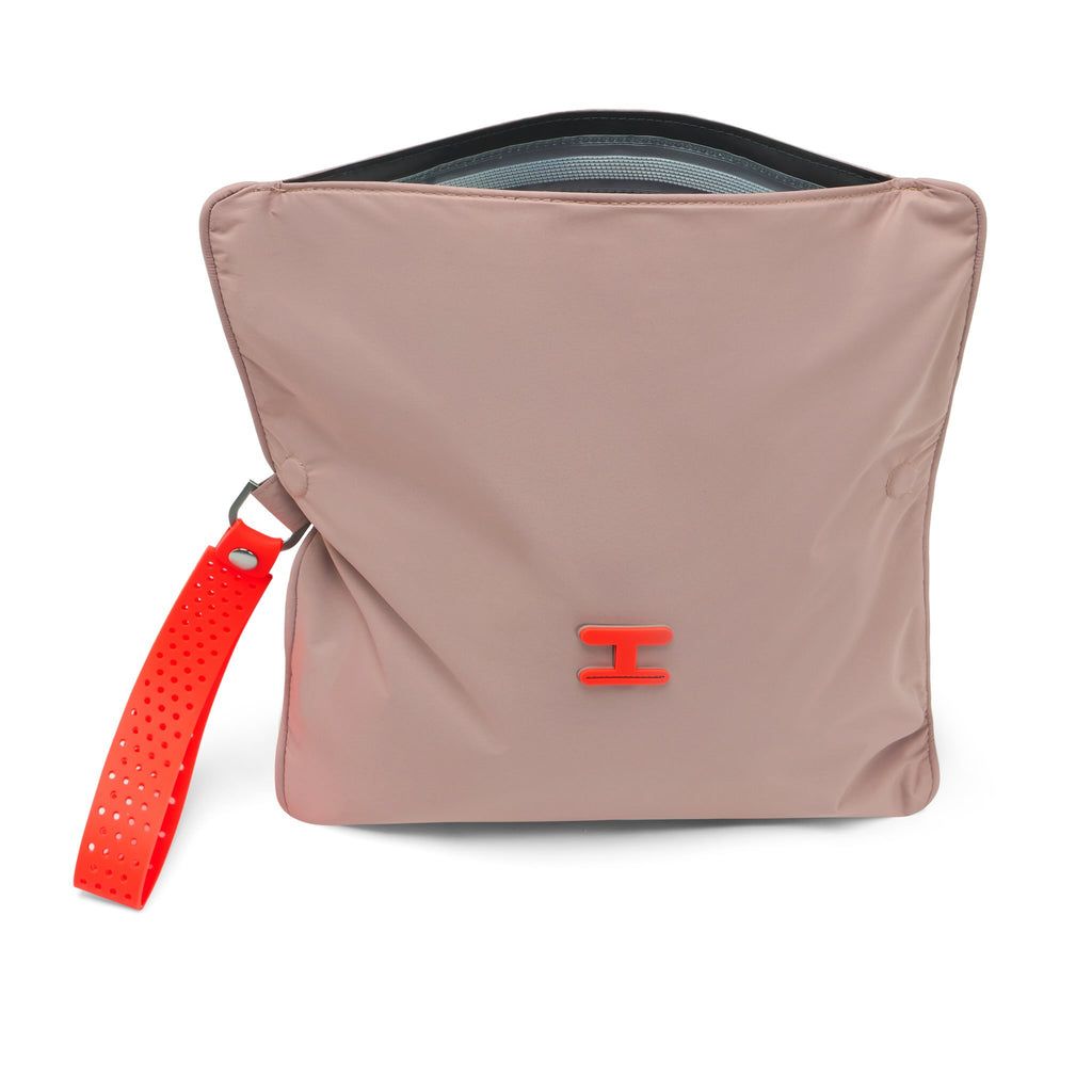 A dusty pink nylon pouch bag with a bright red perforated wrist strap and a small red logo, shown on a clean white background.