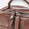 detail photo of zipper closure of a brown leather backpack.