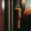 Brown leather punching bag hanging from a chain against a dark background