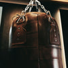 Brown leather punching bag with chain on a dark background