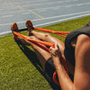 Person using an orange resistance band on a grassy field