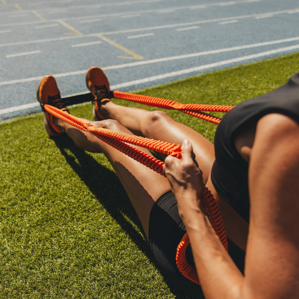 Person using an orange resistance band on a grassy field