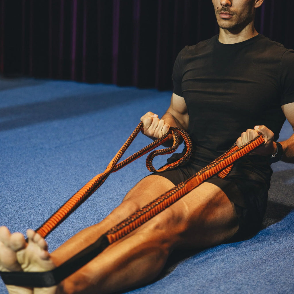 Man exercising with resistance bands on a blue floor.