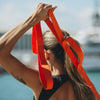 Person using an orange stretch band outdoors with a blurred background