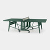 A green portable folding table tennis table with a net and caster wheels, shown on a light gray background.