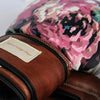 Close-up of a brown leather bag with a floral patterned bag in the background.