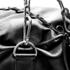 Close-up of a leather bag with metal hardware and chains.