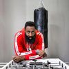 Man in a red hoodie leaning on a foosball table with a punching bag in the background