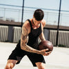 Man with tattoos holding a medicine ball on an outdoor court
